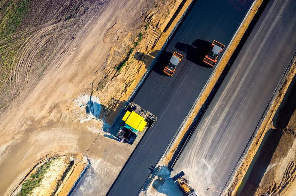 Drone view of asphalt paving works with paver and rollers / Pandangan dari dron bagi kerja penurapan asfalt menggunakan jentera penurap dan penggelek